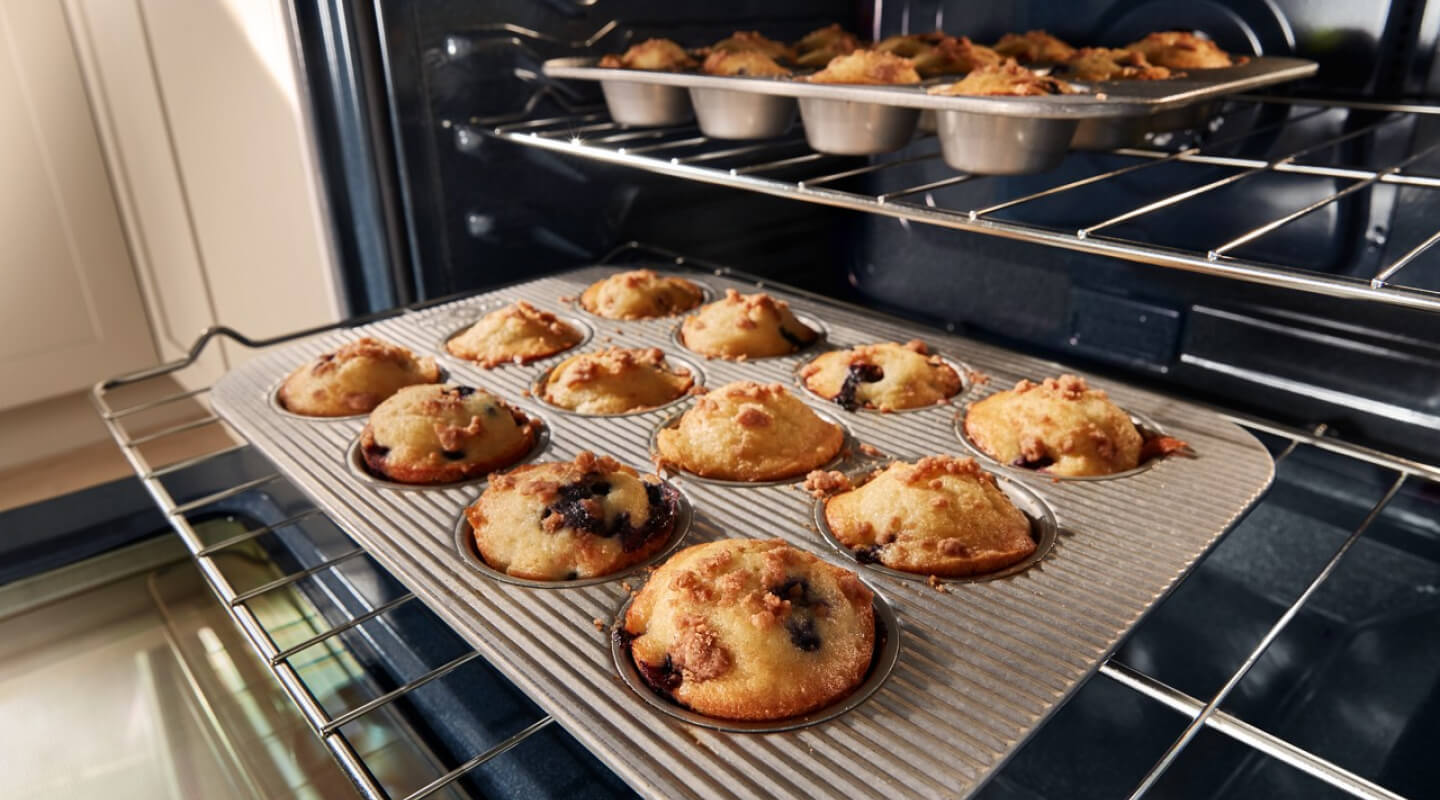 Muffins cooking in pans on two different oven racks Muffins cooking in pans on two different oven racks