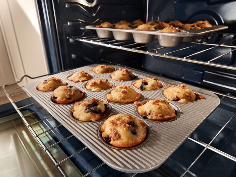 Muffins cooking in pans on two different oven racks Muffins cooking in pans on two different oven racks
