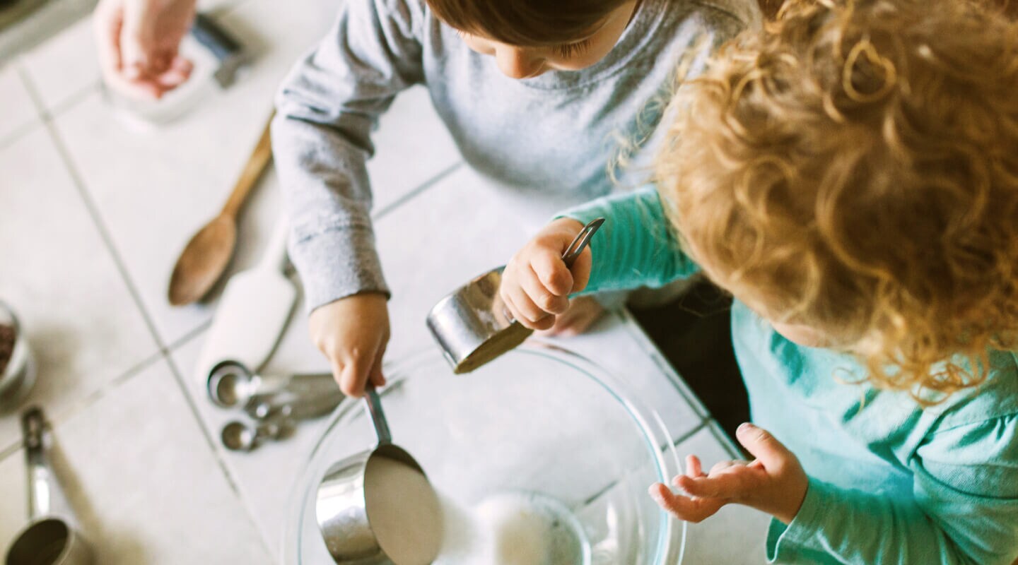Young children pouring ingredients into a bowl Young children pouring ingredients into a bowl