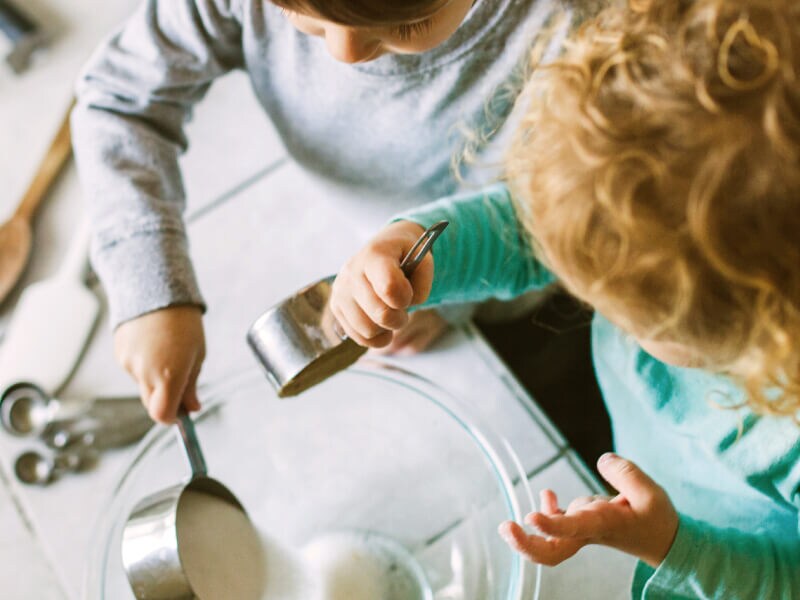 Young children pouring ingredients into a bowl Young children pouring ingredients into a bowl