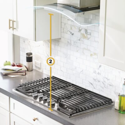 Gas cooktop set into gray countertop with measurements noted for distance from cooking surface to vent hood