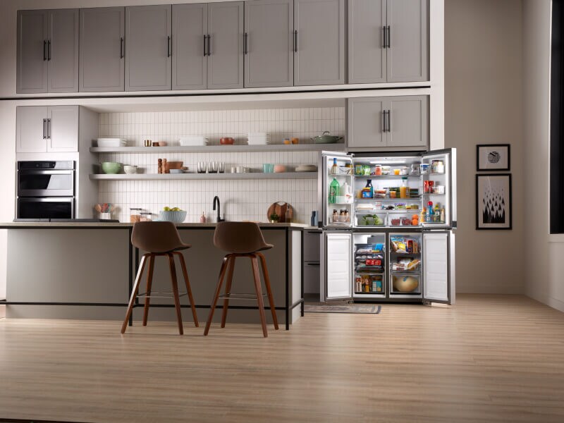 The inside of a kitchen with a counter-depth refrigerator shown with its doors open