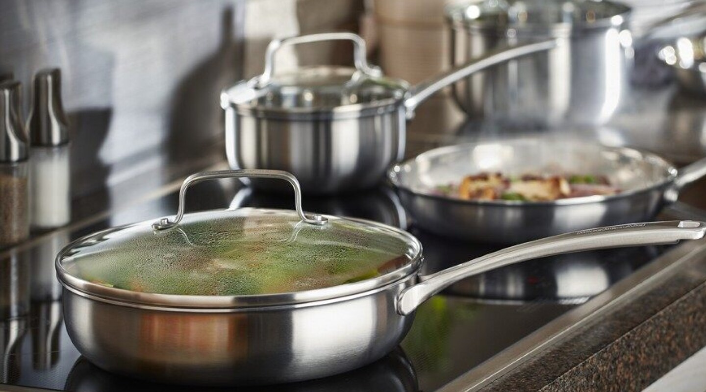 Various pots and pans cooking food on a cooktop Various pots and pans cooking food on a cooktop