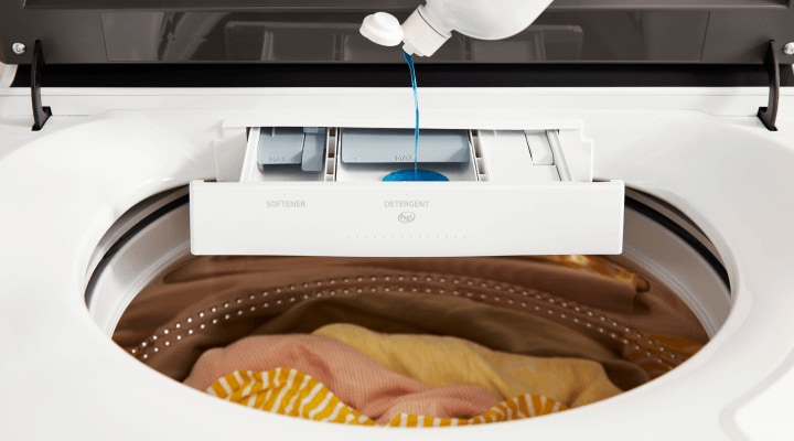 Person adding detergent to a washing machine Person adding detergent to a washing machine