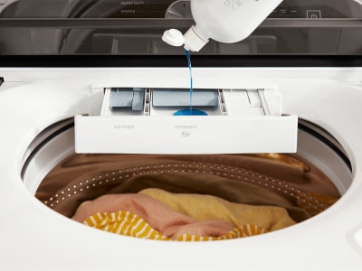 Person adding detergent to a washing machine Person adding detergent to a washing machine
