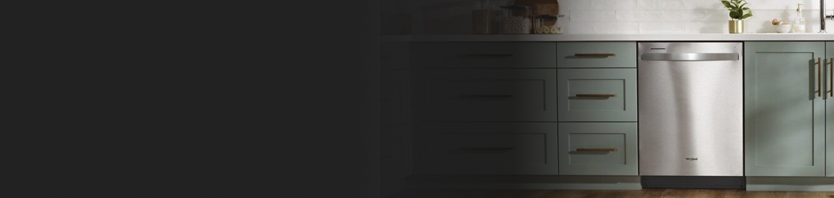 Stainless steel dishwasher in gray-green cabinetry. 