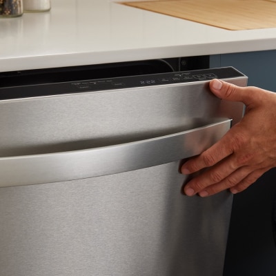 A person closing the door of a dishwasher A person closing the door of a dishwasher