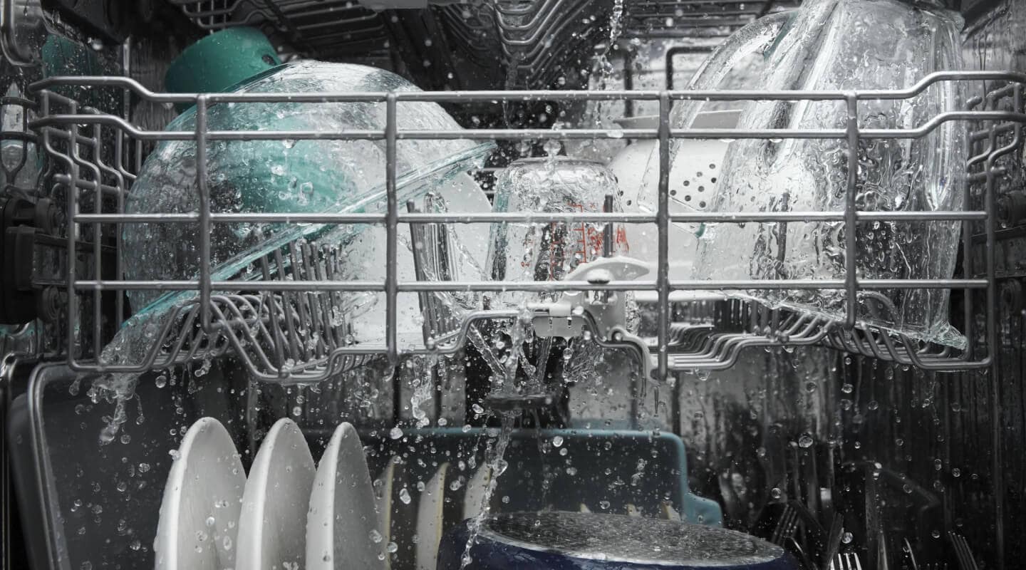 Dishes being rinsed with water inside a dishwasher