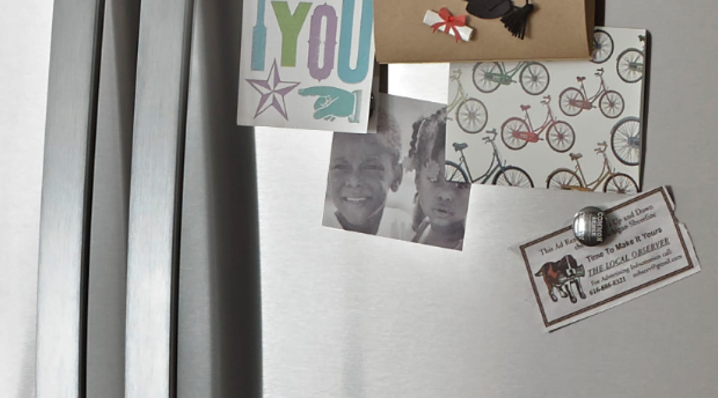A close up of cards and a photo stuck to a fridge with magnets
