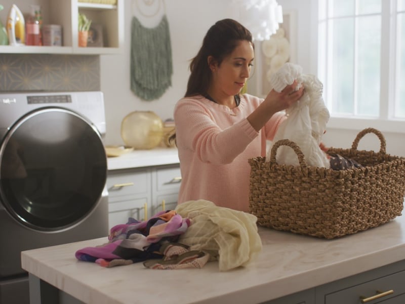 Person loading clothes into laundry basket Person loading clothes into laundry basket