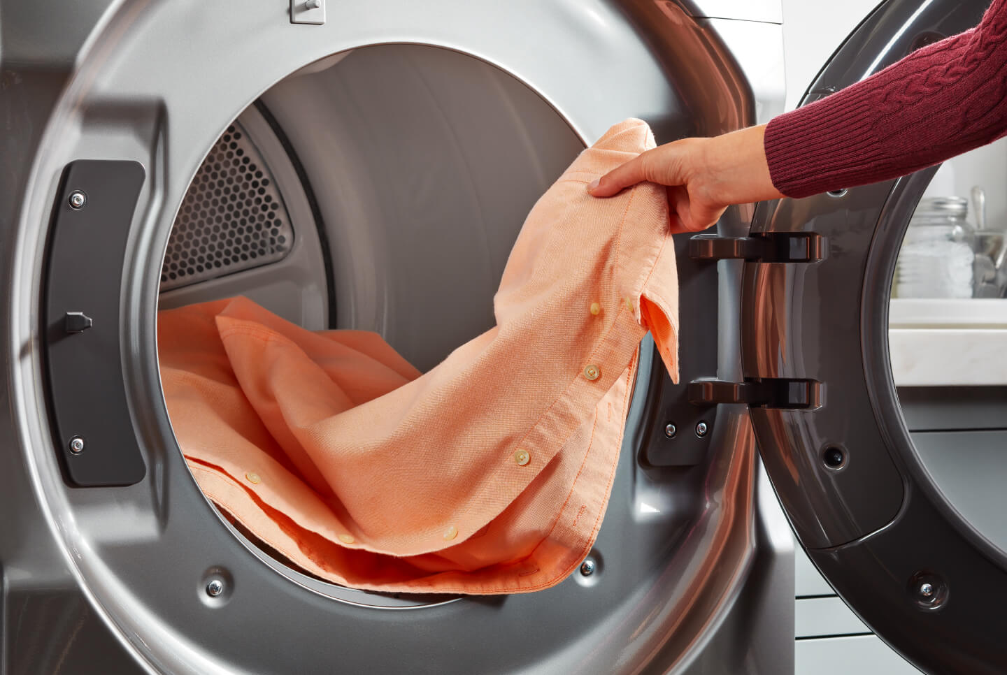 Person loading shirt in dryer Person loading shirt in dryer