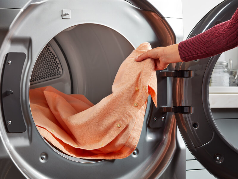 Person loading shirt in dryer Person loading shirt in dryer