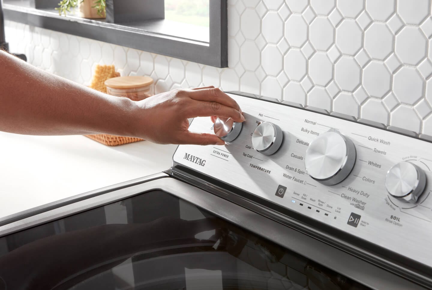 Person turning knob on washing machine Person turning knob on washing machine