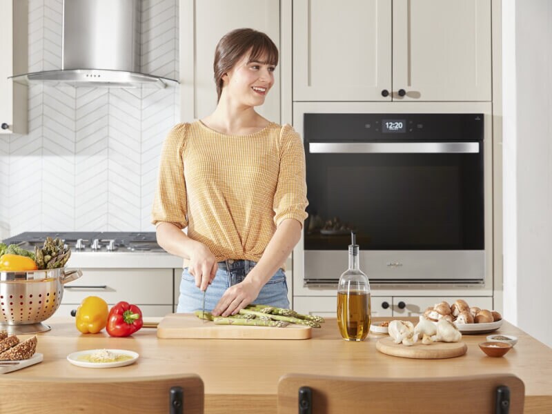 Person standing at a kitchen island chopping vegetables on a cutting board