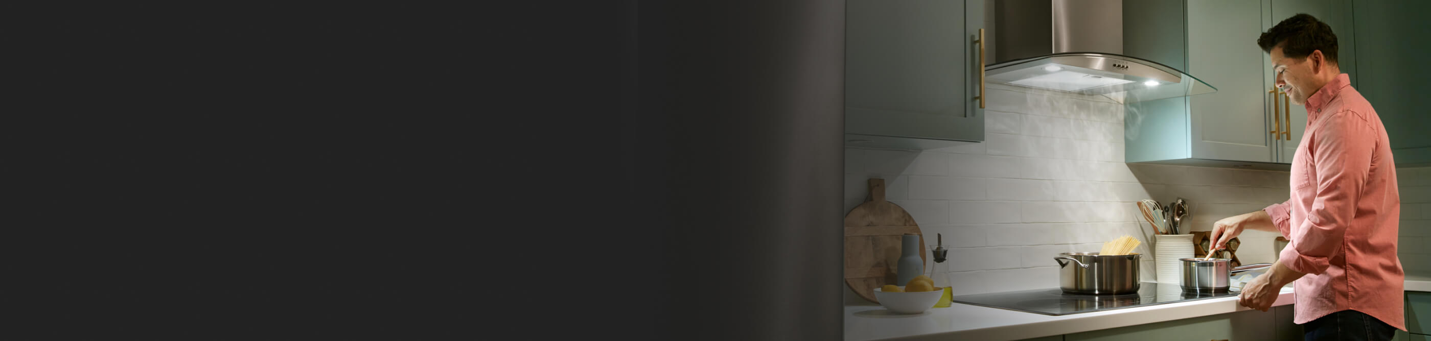 Person cooking on a cooktop with a wall mount range hood above