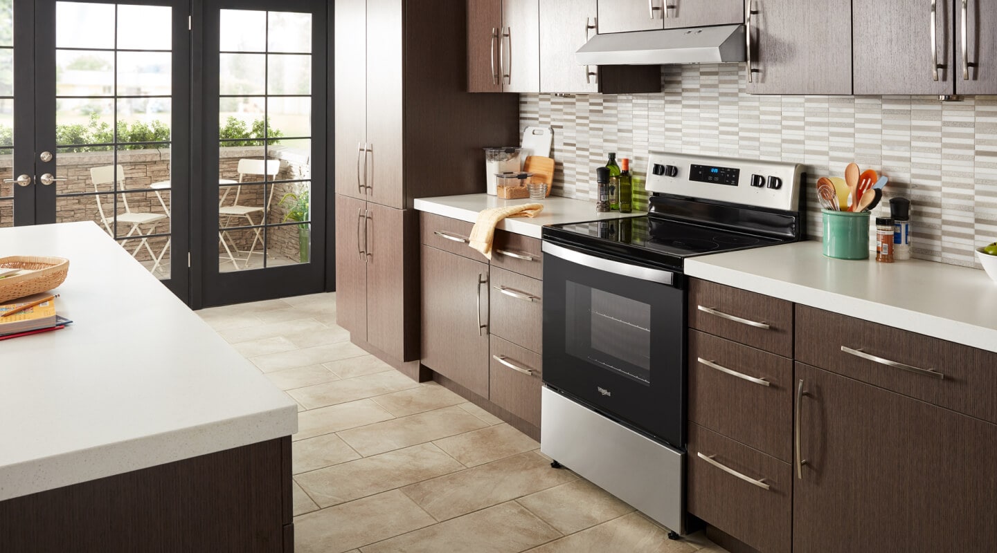 Whirlpool® electric range in a modern kitchen with a range hood above Whirlpool® electric range in a modern kitchen with a range hood above