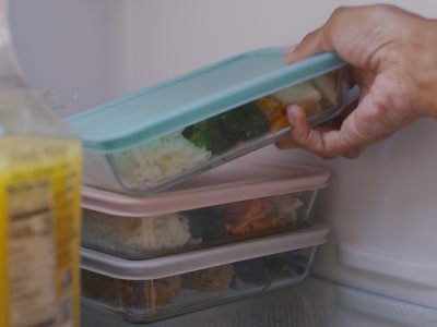 A person placing leftovers in the fridge A person placing leftovers in the fridge