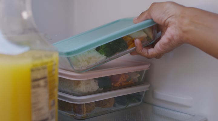 A person placing leftovers in the fridge A person placing leftovers in the fridge