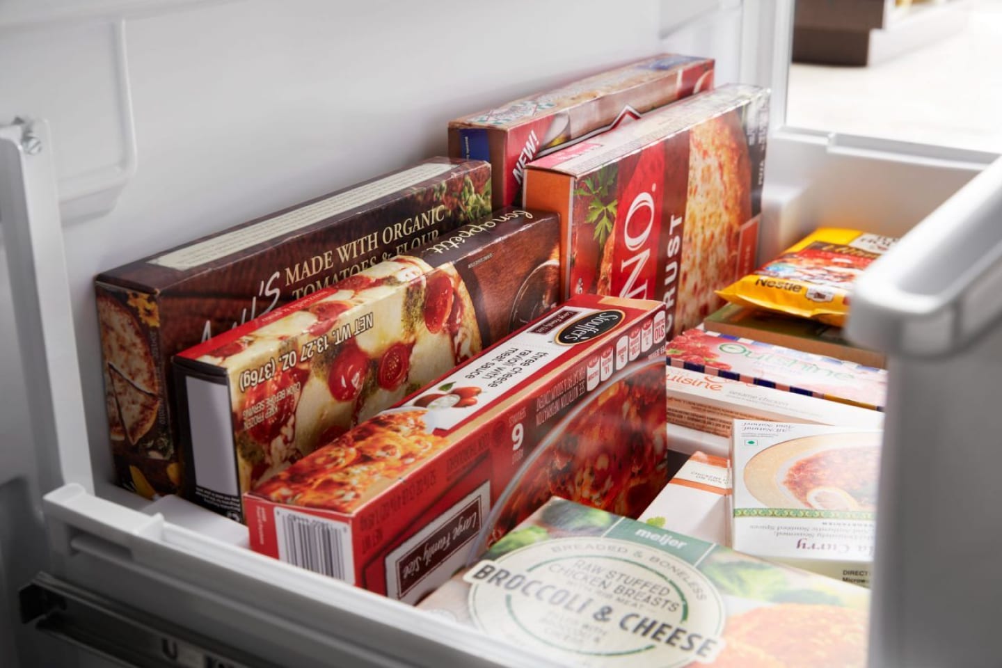Close-up of frozen pizzas and other foods in an open bottom freezer Close-up of frozen pizzas and other foods in an open bottom freezer