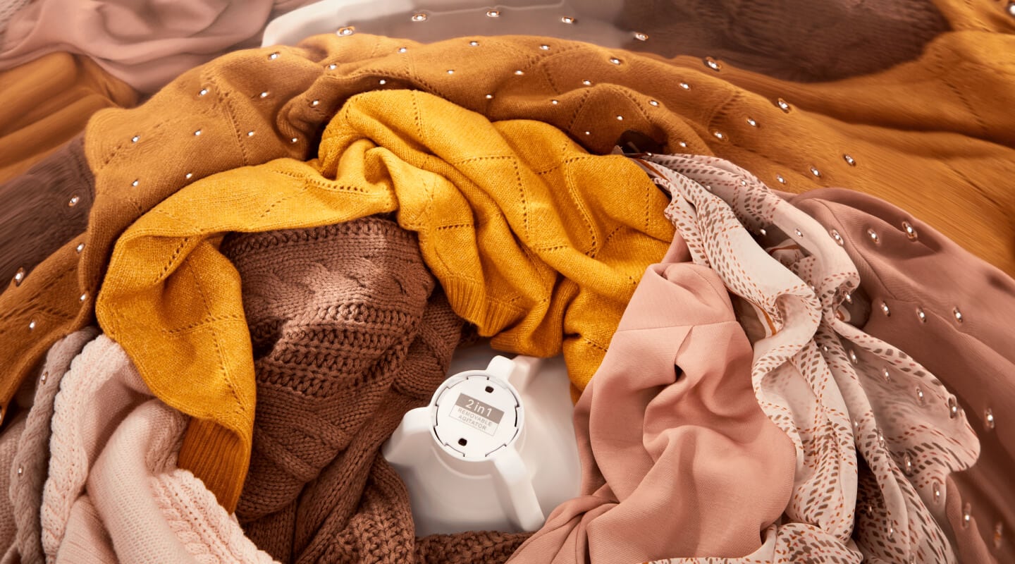 Orange- and pink-toned clothes inside of a Whirlpool® Washer with the 2 in 1 Removable Agitator Orange- and pink-toned clothes inside of a Whirlpool® Washer with the 2 in 1 Removable Agitator
