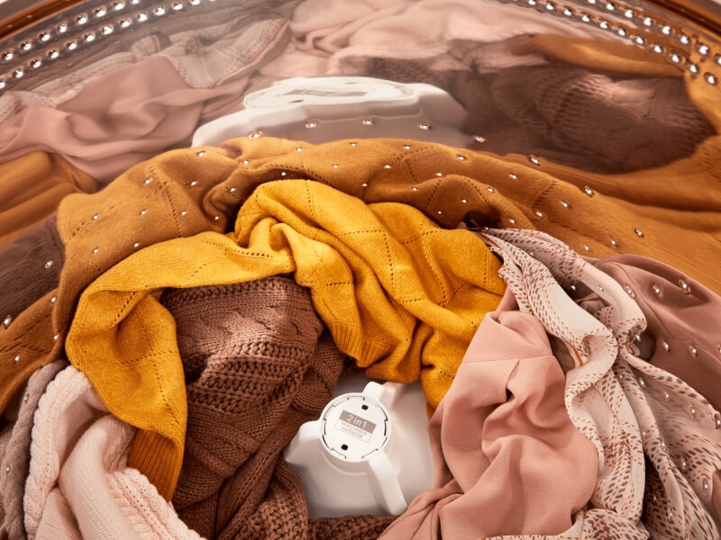 Orange- and pink-toned clothes inside of a Whirlpool® Washer with the 2 in 1 Removable Agitator Orange- and pink-toned clothes inside of a Whirlpool® Washer with the 2 in 1 Removable Agitator