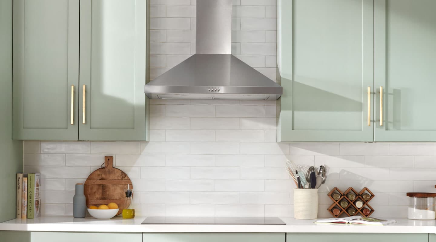 A stainless steel range hood above a cooktop A stainless steel range hood above a cooktop