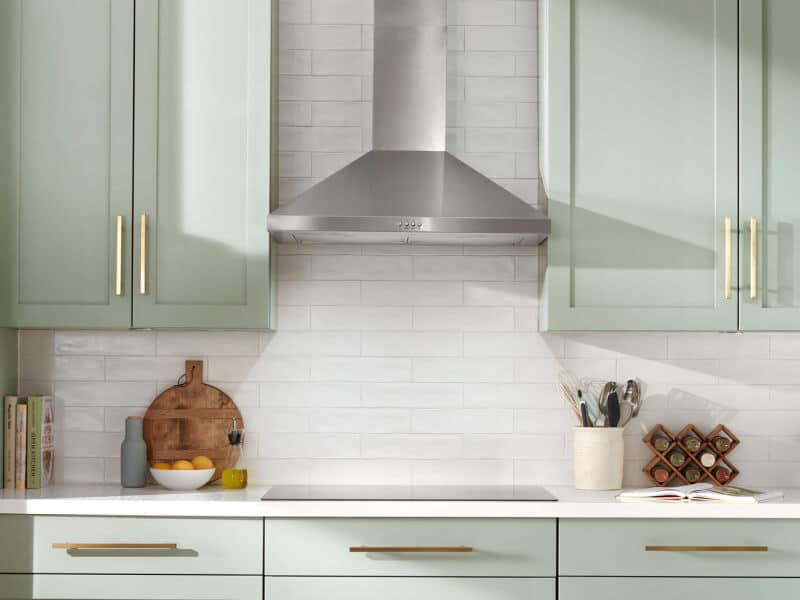 A stainless steel range hood above a cooktop A stainless steel range hood above a cooktop