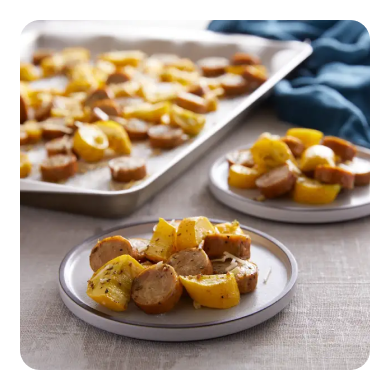 Two plates full of sliced yellow squash and chicken sausage Two plates full of sliced yellow squash and chicken sausage