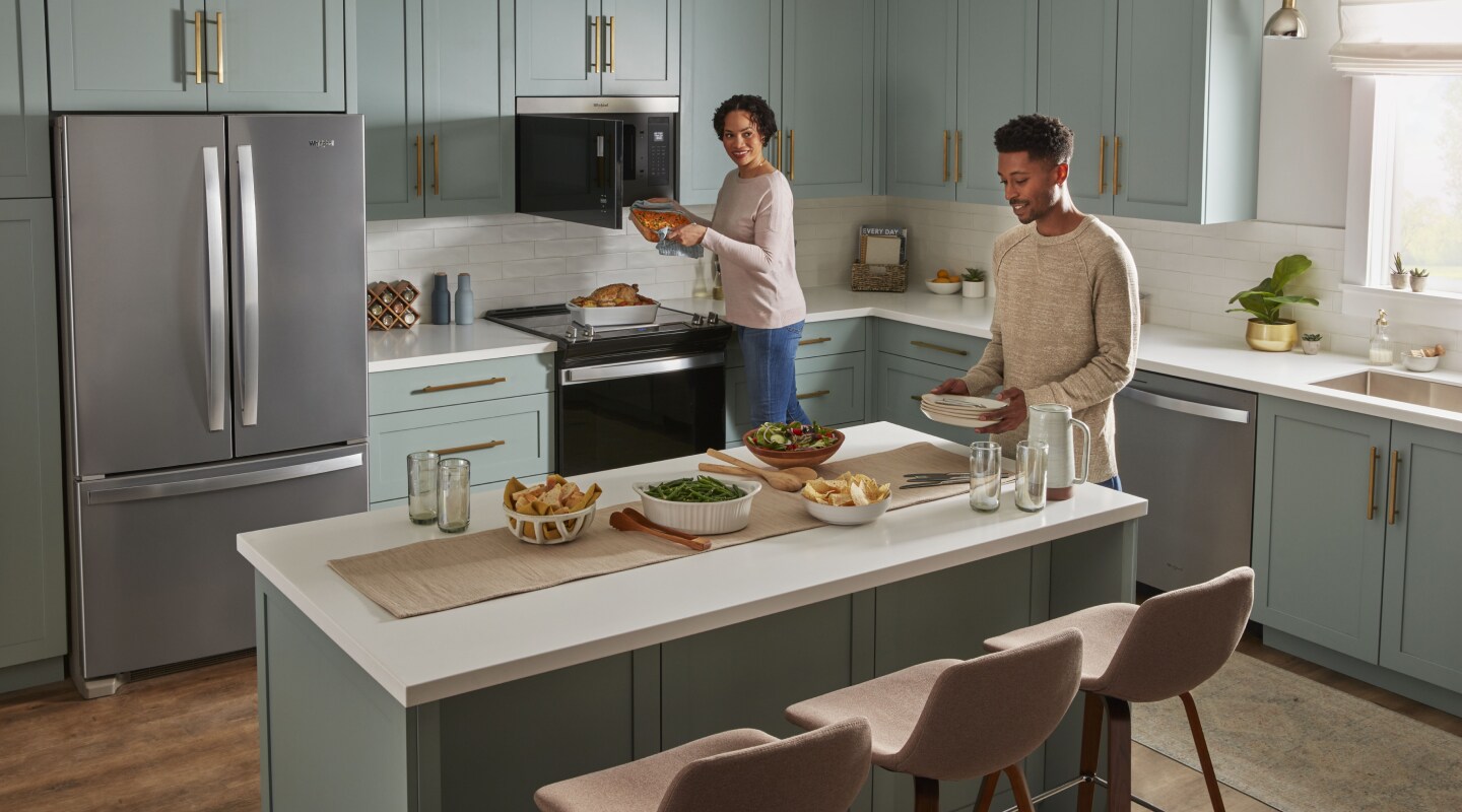 Person retrieving a casserole dish from a Whirlpool® over-the-range microwave