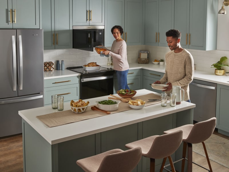 Person retrieving a casserole dish from a Whirlpool® over-the-range microwave
