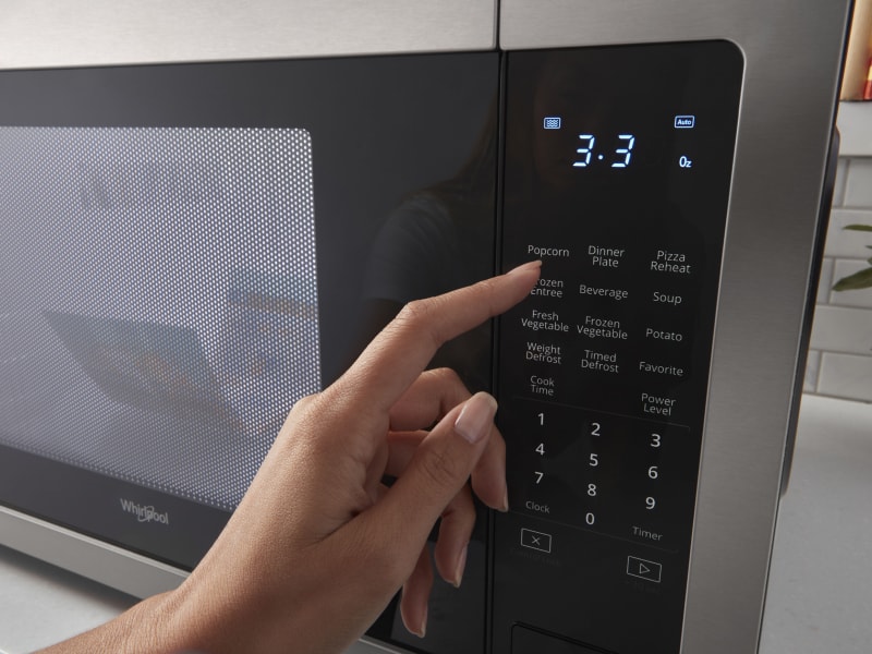 Person selecting settings on a microwave touchpad 