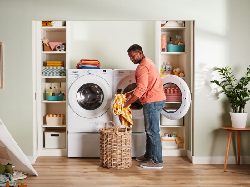 A person pulling clothes out of a dryer A person pulling clothes out of a dryer