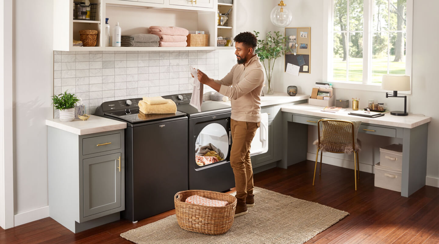 A person pulling clothes out of a dryer A person pulling clothes out of a dryer