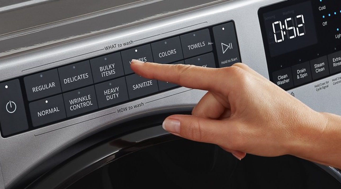 A person selecting washer settings on a control panel