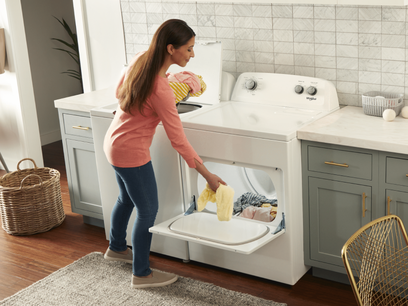 Person placing clothes into a Whirlpool® front load dryer. Person placing clothes into a Whirlpool® front load dryer.