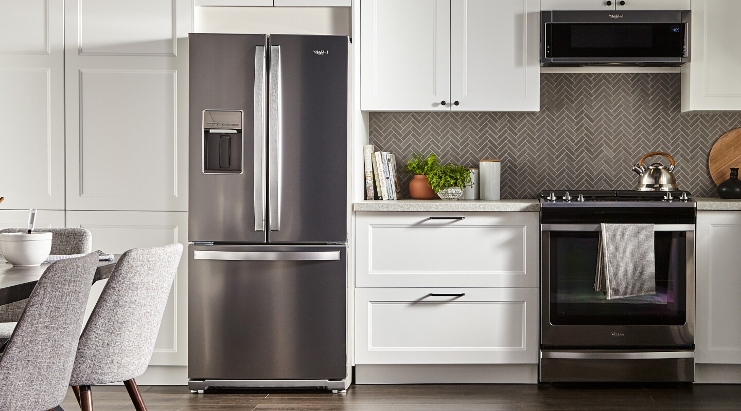 Stainless steel French door refrigerator in kitchen with white cabinetry