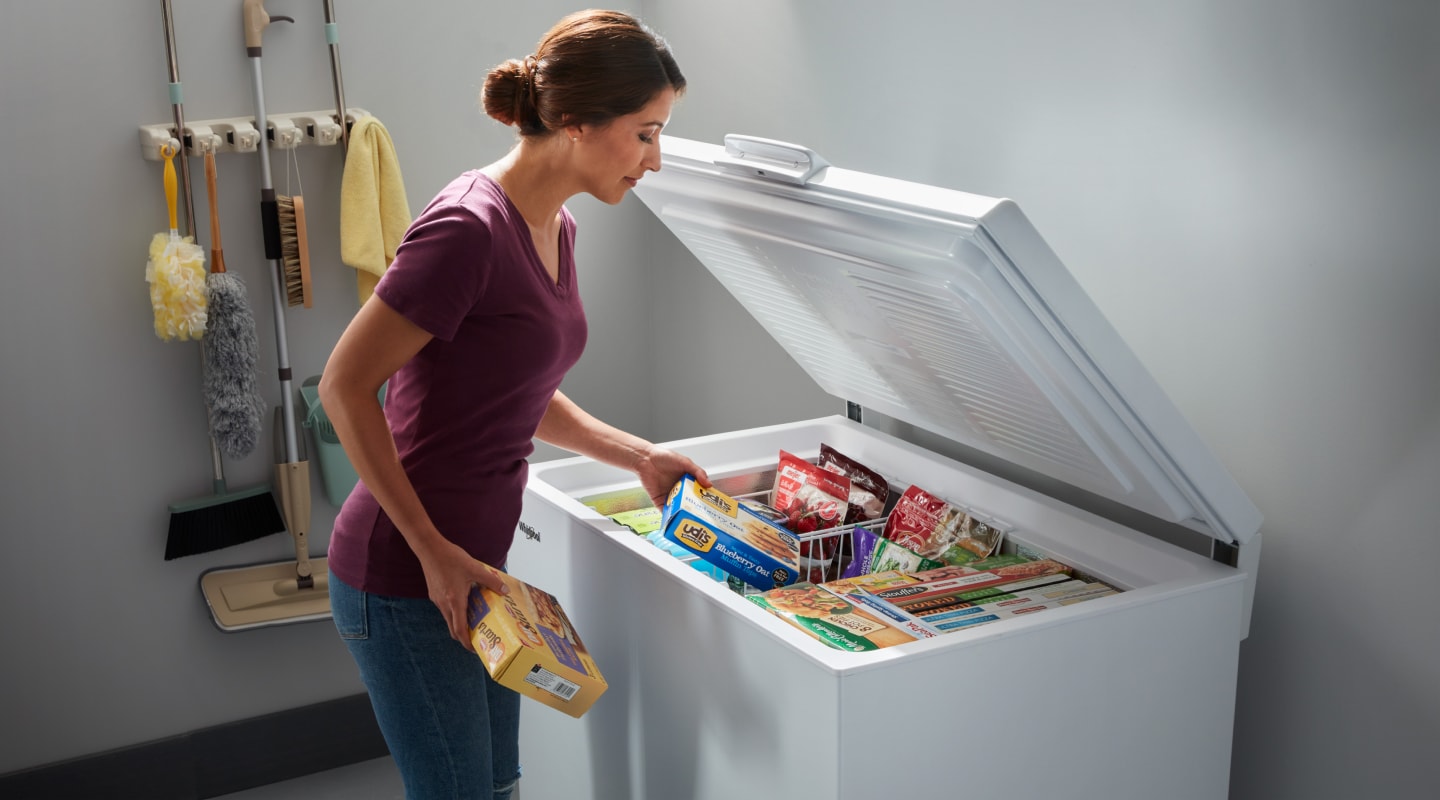 Person loading food into a chest freezer Person loading food into a chest freezer