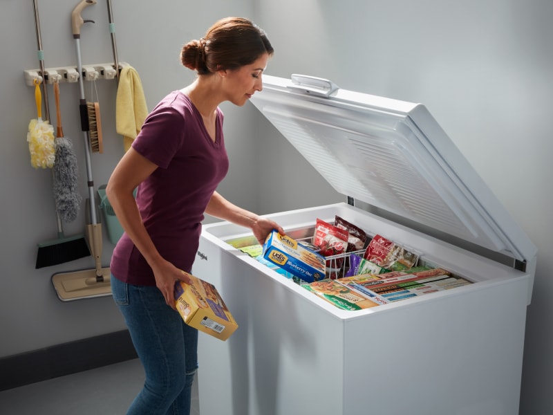 Person loading food into a chest freezer Person loading food into a chest freezer