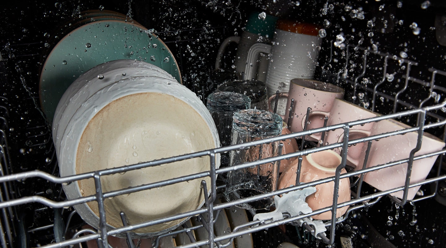 The interior of a Whirlpool® dishwasher cleaning dishes during a wash cycle. The interior of a Whirlpool® dishwasher cleaning dishes during a wash cycle.