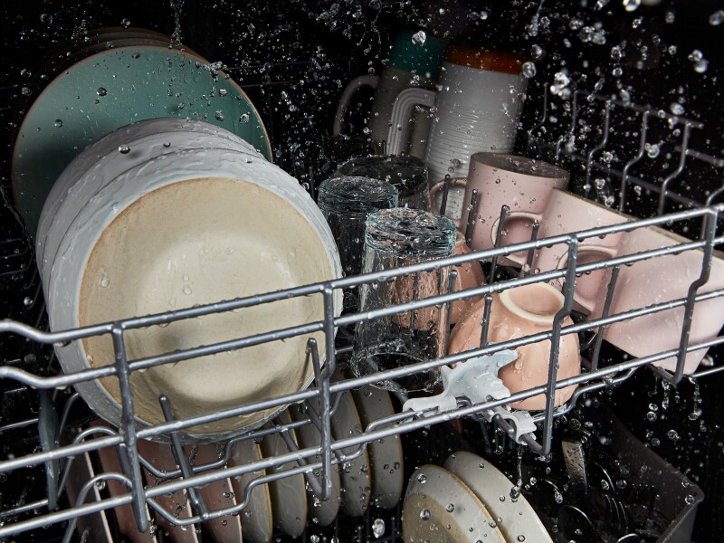The interior of a Whirlpool® dishwasher cleaning dishes during a wash cycle. The interior of a Whirlpool® dishwasher cleaning dishes during a wash cycle.