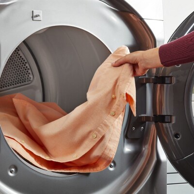 Hand pulling an item of clothing out of a dryer