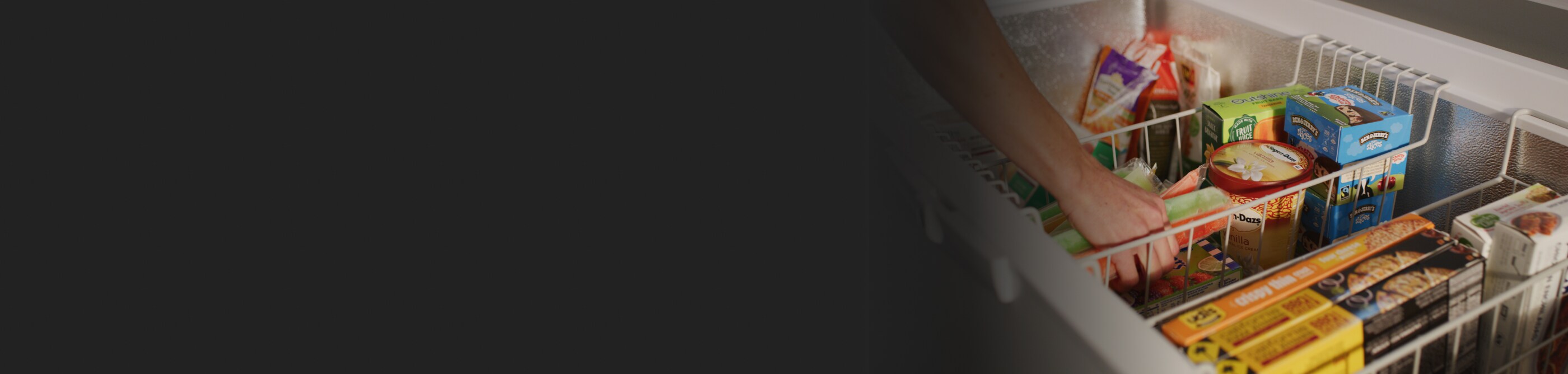 A person grabbing freeze pops out of a bottom drawer freezer. Image 1: A white Whirlpool® deep freezer.