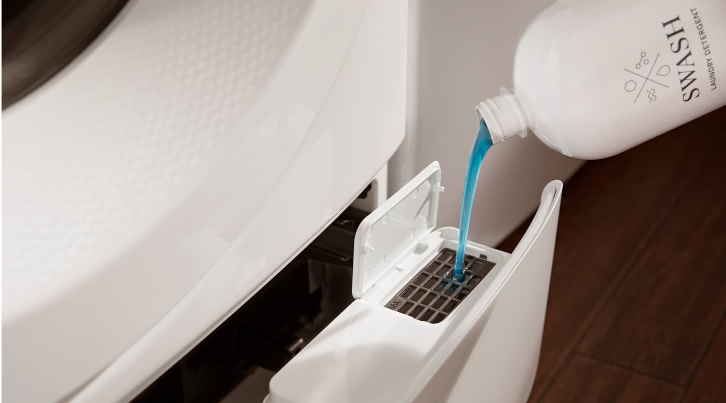 Detergent pouring into a detergent dispenser on a white washing machine