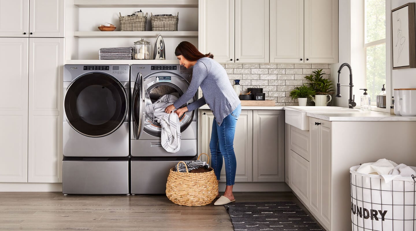 Woman loading towels into a Whirlpool® stainless steel dryer Woman loading towels into a Whirlpool® stainless steel dryer