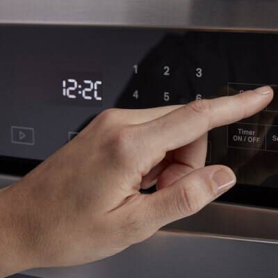 Person selecting a setting on an oven control panel