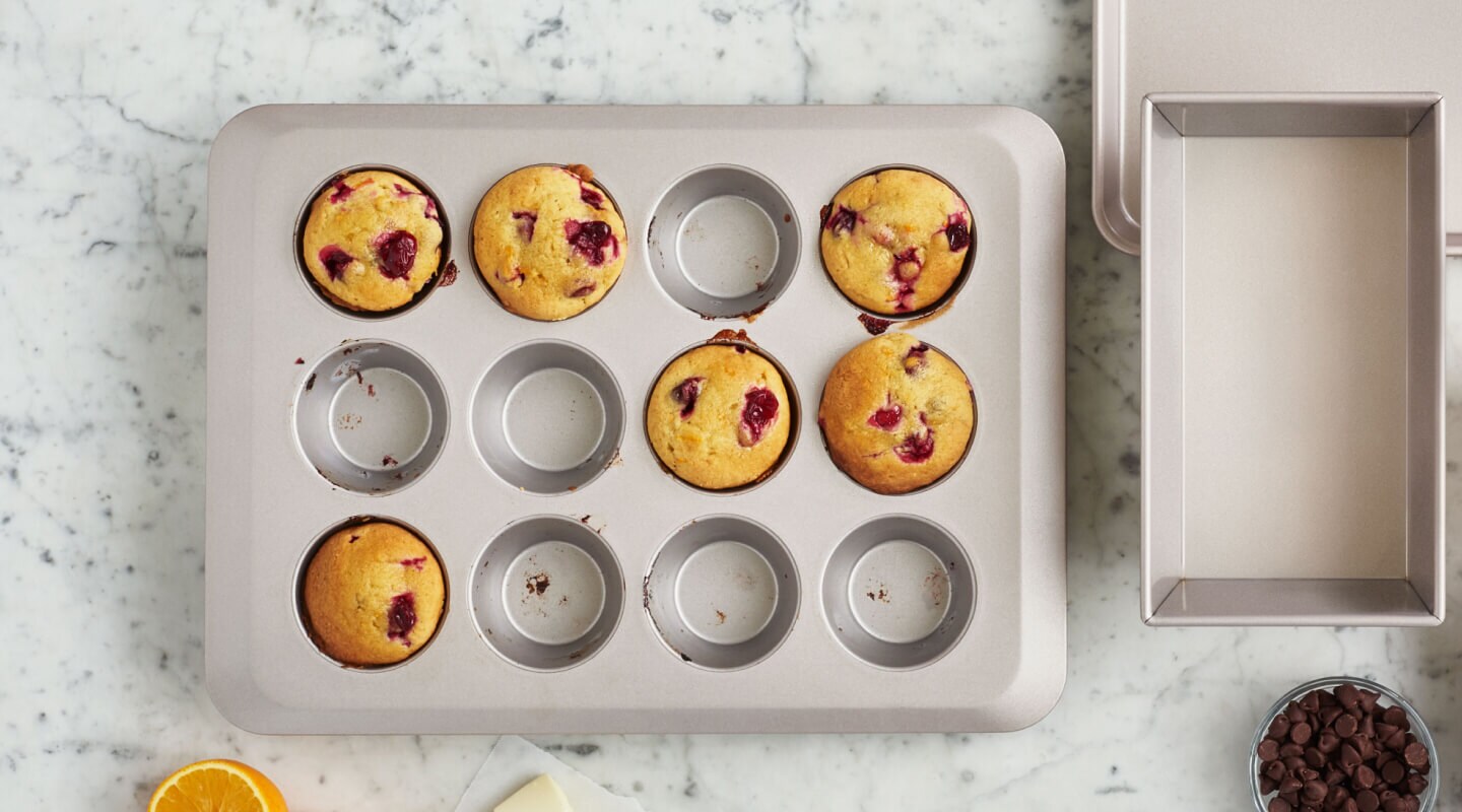 A muffin tin with cranberry muffins in 6 of the 12 cups A muffin tin with cranberry muffins in 6 of the 12 cups