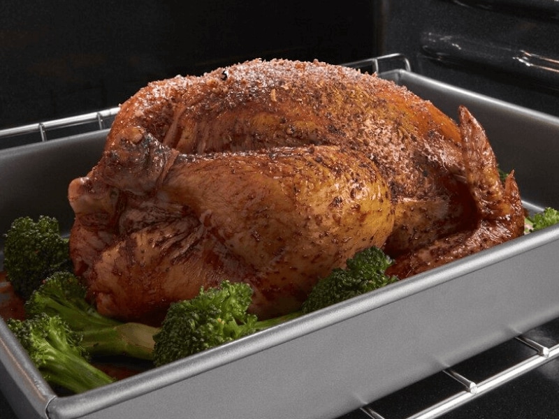 Seasoned cooked turkey in a roasting pan surround by stalks of broccoli Seasoned cooked turkey in a roasting pan surround by stalks of broccoli