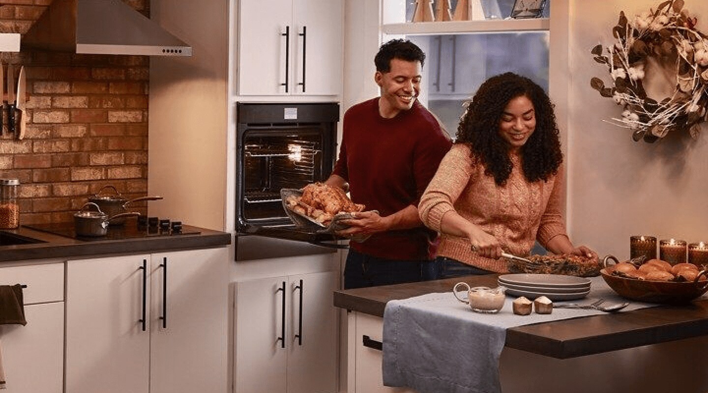 Smiling people preparing a turkey dinner in a modern kitchen Smiling people preparing a turkey dinner in a modern kitchen