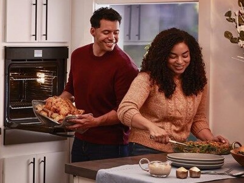 Smiling people preparing a turkey dinner in a modern kitchen Smiling people preparing a turkey dinner in a modern kitchen