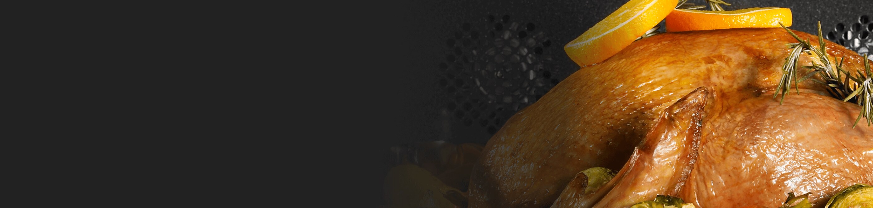 A turkey cooking in an oven garnished in rosemary and orange slices